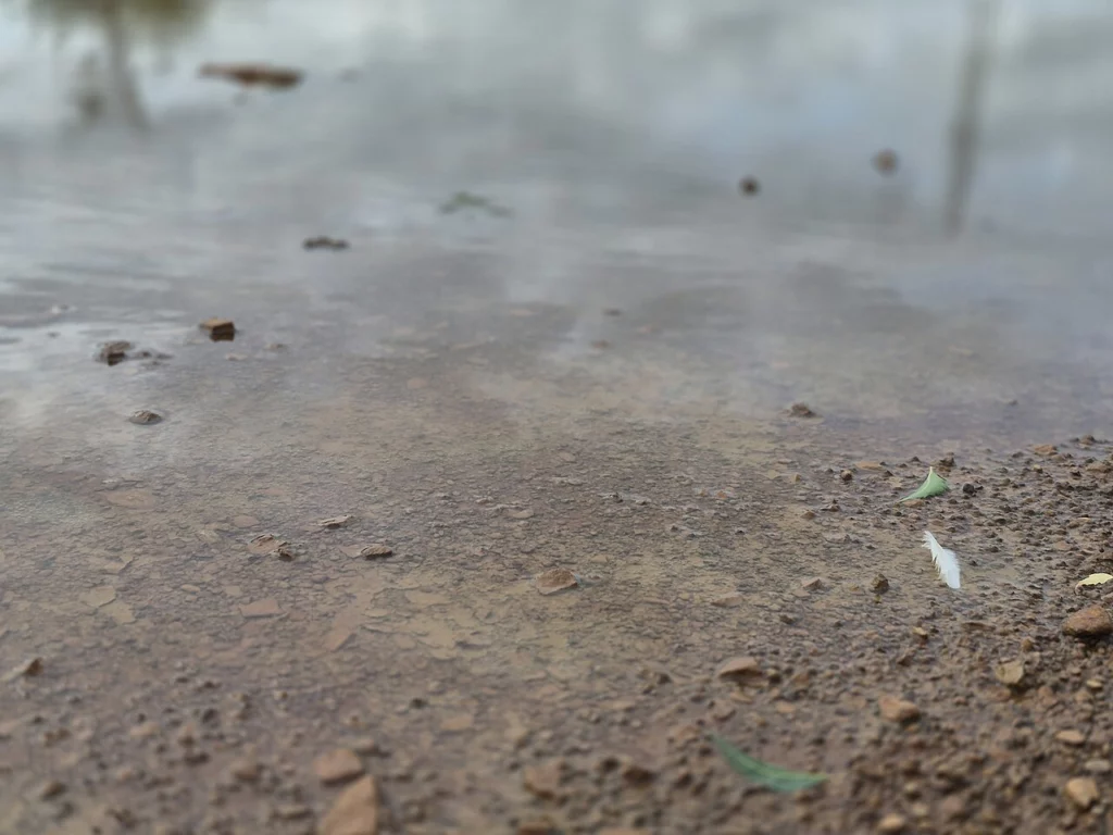 Стакан мутной воды с мелким песком на дне рядом с краном