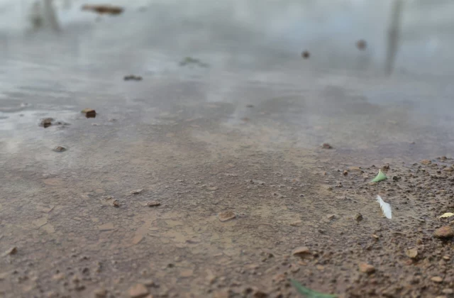 Стакан мутной воды с мелким песком на дне рядом с краном